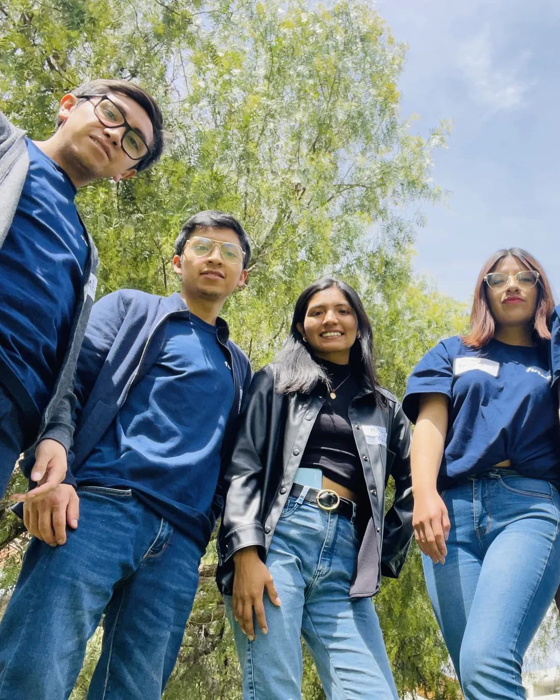 Cuatro integrantes de futurX con la camiseta azul, fotografiados desde abajo en el campus.