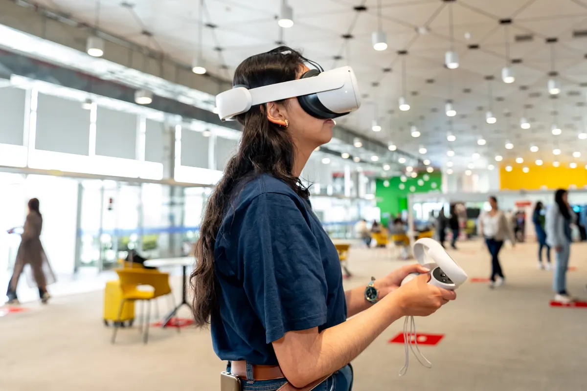 Una asistente prueba un visor de realidad virtual con los mandos en las manos.